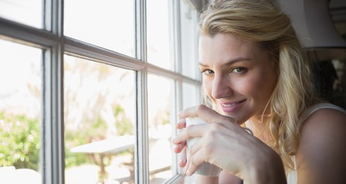 Woman looking out of window with coffee